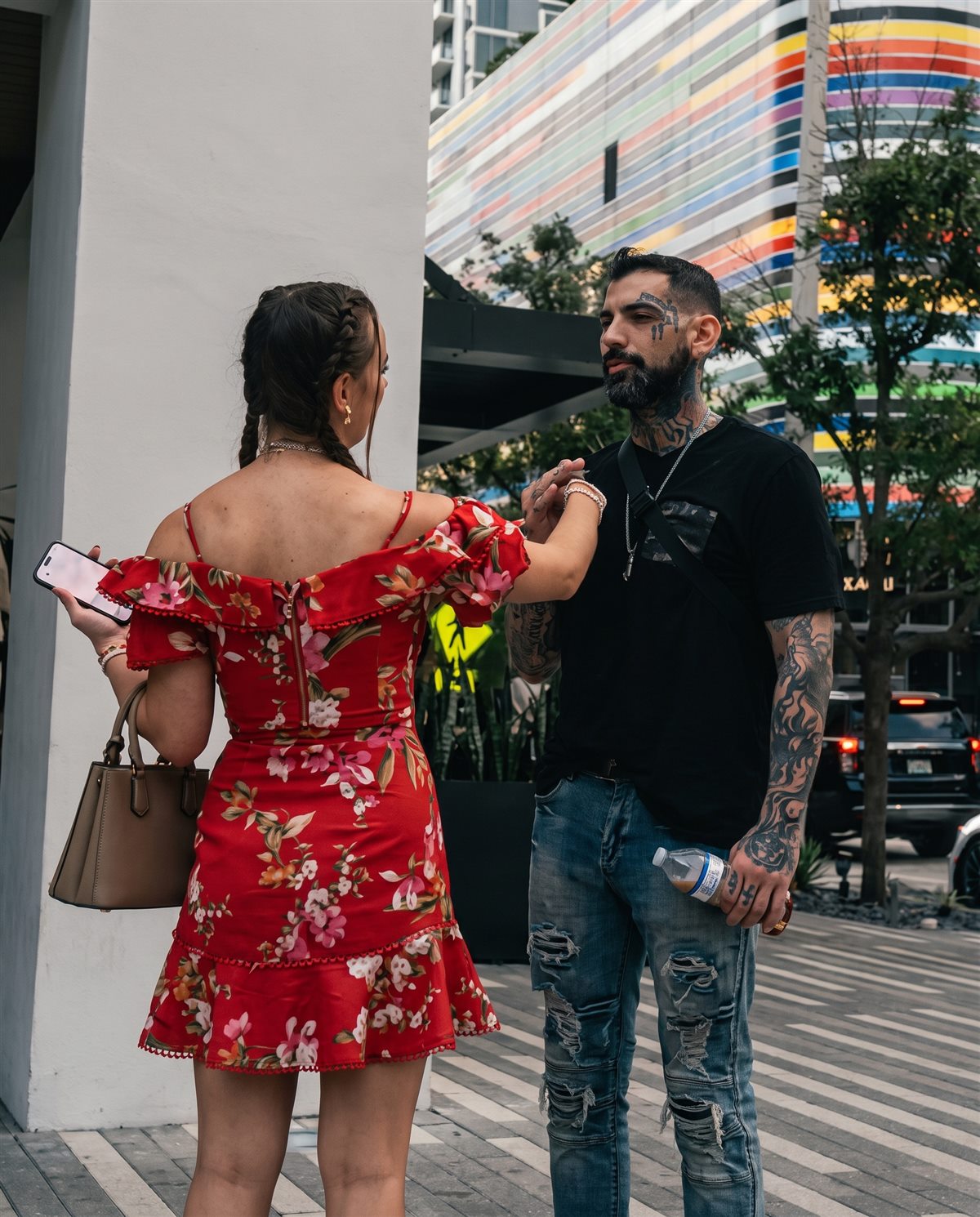 Scotty mid-conversation with a woman in a red floral dress on a city sidewalk